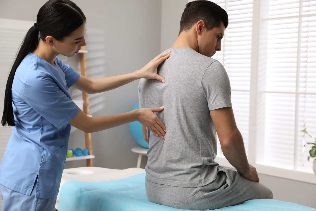 Orthopedist Examining Man's Back in Clinic. Scoliosis Treatment
